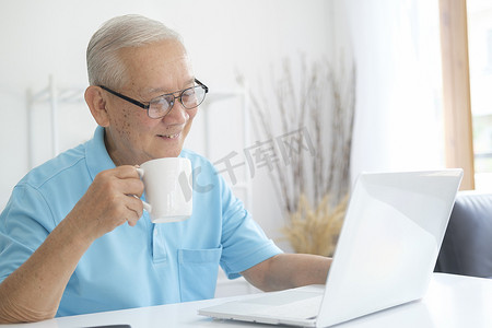老人在家使用笔记本电脑上网。