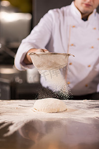 厨师在新鲜的披萨面团上撒上面粉