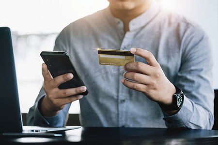 网上购物和互联网支付，亚洲男性正在使用信用卡和手机在数字世界中网上购物或办事。