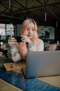 漂亮的女学生，带着可爱的微笑，在大学讲座后放松时在上网本上敲键盘，美丽的快乐女人在咖啡馆喝咖啡休息时在笔记本电脑上工作