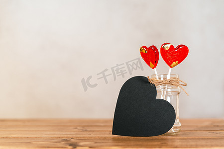 静物画情人节节日背景与空黑黑板心和木制背景上的 2 个棒棒糖。