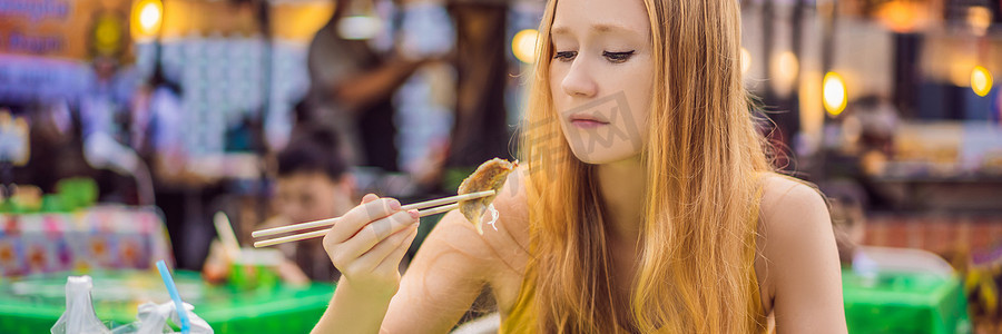 长摄影照片_快乐可爱的女孩吃着街头小吃，在传统的小集市横幅中看起来很愉快，长格式