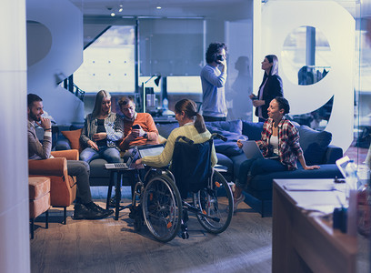 坐在轮椅上的残疾人女商人在办公室与多元化的业务团队进行头脑风暴会面