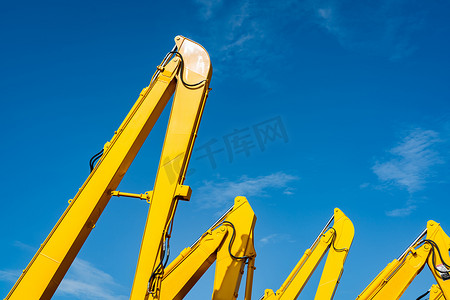 黄色反摄影照片_黄色反铲与液压活塞臂反对清澈的蓝天。