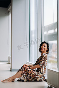 坐着老虎摄影照片_一个穿着虎裙的黑发美女坐在室内的一扇大窗户前