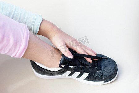 泰国曼谷，2018年7月18日-儿童手触黑色运动鞋品牌阿迪达斯
