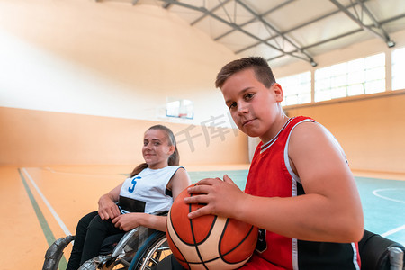 男孩坐在轮椅上，为大球馆的篮球比赛开始做准备。