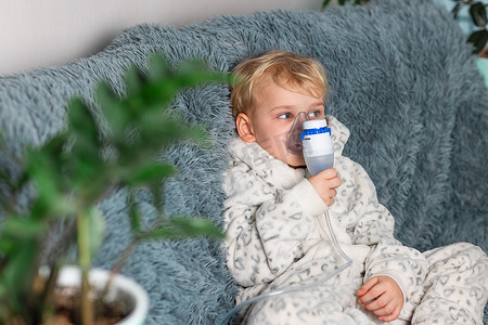 可爱的小男孩用雾化器设备吸入。