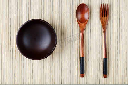 竹盘子摄影照片_浅竹背衬上天然木材制成的空深色木杯、勺子和叉子