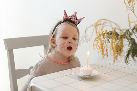 可爱的小女孩吹灭家里生日蛋糕上的蜡烛。