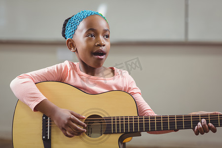 可爱的学生在教室里唱歌弹吉他