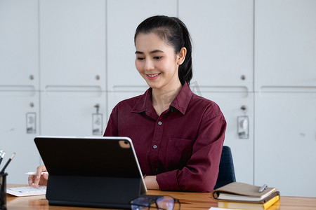 在销售增长增加后，一位美丽的女人微笑着高兴地在平板电脑屏幕上使用销售利润计算器。