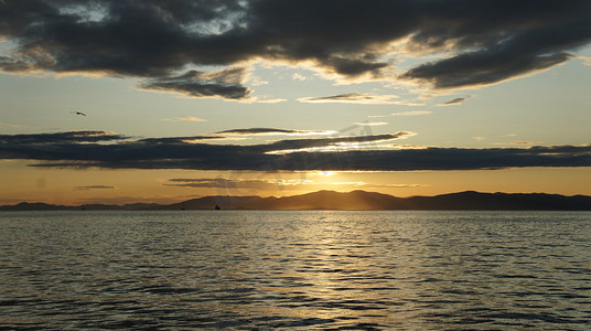 太阳橙色摄影照片_海上美丽的橙色日落，远处的岛屿