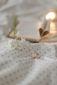 婚礼金戒指和打开的书，床上有心形折叠床单。