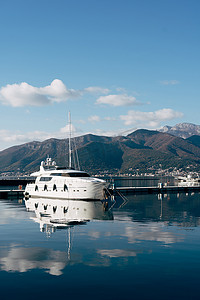 码头上的白色单层游艇，背景是山脉