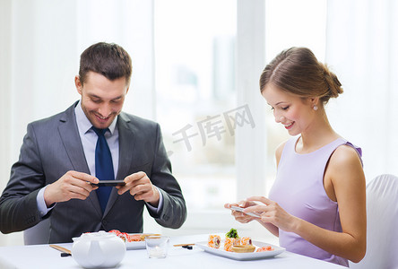 微笑的夫妇拿着寿司和智能手机