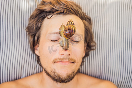 男士spa摄影照片_年轻人用蜗牛粘液制作面膜。