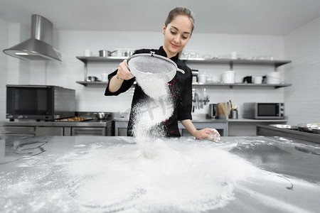 糕点师将面粉通过筛子撒在桌子上