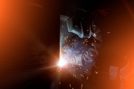 一名工人电焊工在半自动化工厂里烧钢。