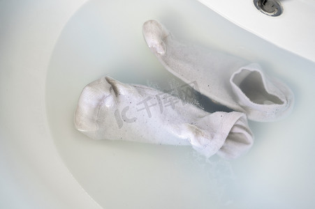 脏袜子摄影照片_在水槽水中清洗脏袜子
