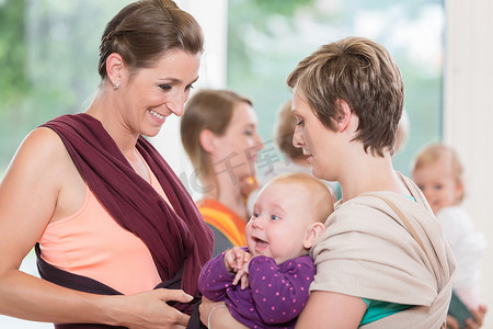 年轻女性学习如何使用婴儿背带来抱孩子
