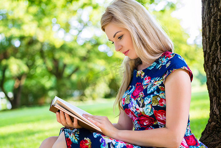 读书的女人摄影照片_夏季公园草地上读书的女人