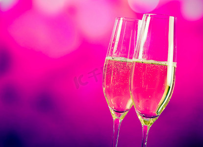 紫色气泡饮料摄影照片_蓝色和紫色浅色背景上带有金色气泡的香槟笛