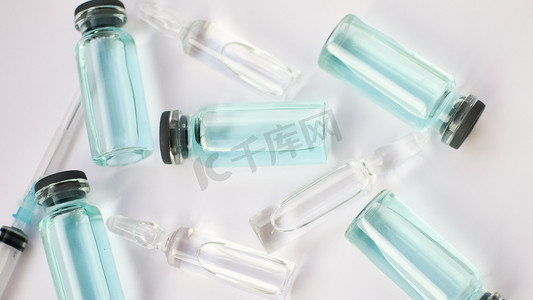 小瓶疫苗、白色背景上透明蓝色液体的玻璃安瓿顶视图、全球疫苗接种概念