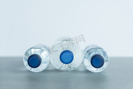 蓝色的矿泉水瓶子摄影照片_三个装满矿泉水的塑料瓶躺着