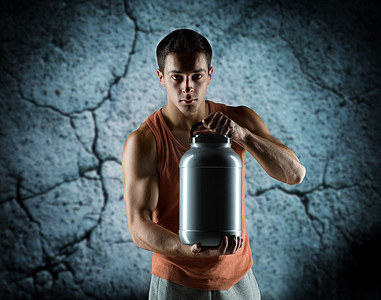 年轻男性健美运动员拿着装有蛋白质的罐子