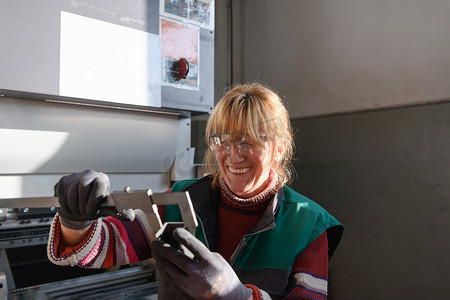 一名妇女在现代化金属生产和加工工厂工作，准备和测量用于数控机床加工的材料