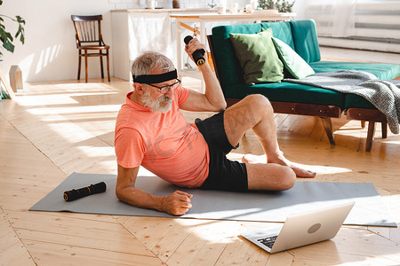 老人摄影照片_老人用哑铃在家做健身运动 — 老年人与健康概念