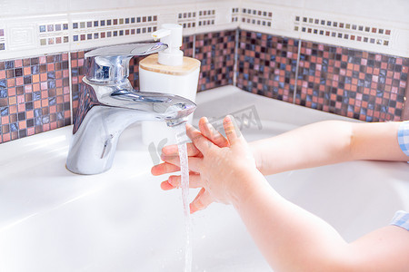 洗手摄影照片_在水龙头下用儿童肥皂用水洗手。