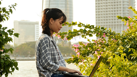 越南亚裔女学生在市中心使用笔记本电脑。
