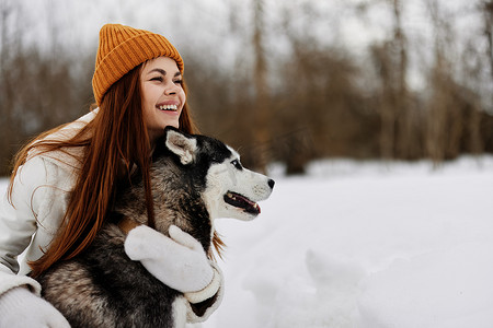 冬天遛狗摄影照片_性格开朗的女人冬装在雪地里遛狗