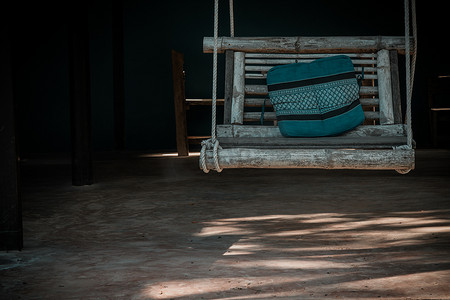 竹秋千椅挂在绳子上，配有坐垫，可供放松的角落。