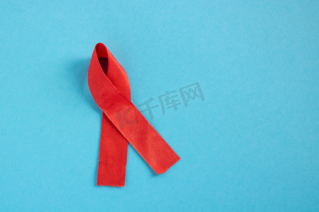 蓝色背景上的红丝带是世界艾滋病日、捐助者日、血友病日的概念。