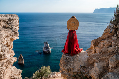 大海背景下，身穿飞扬红裙、头戴草帽的女子随风飘扬。