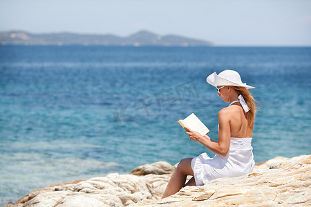 年轻女子在海滩上读书