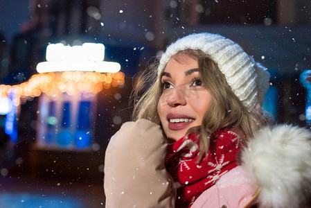 街上一位可爱的女士，穿着冬季夹克，在城市的夜晚灯光下幸福地微笑，她正在等待奇迹