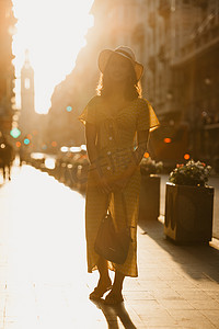 西班牙日落时，一位戴帽子、穿黄色裙子、拿着皮包的女人