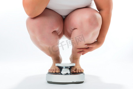 指数摄影照片_肥胖的年轻女子蹲在体重秤上