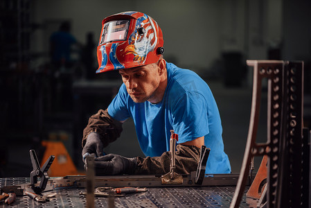 重工业工厂摄影照片_专业重工业焊工在工厂内工作，戴着头盔并开始焊接。