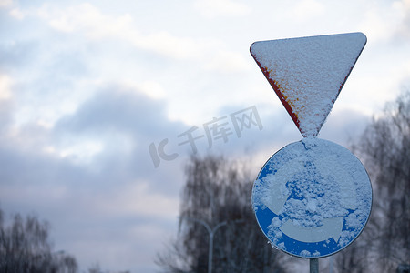 下雪路摄影照片_雪路标志，与环形交通的交叉路口。