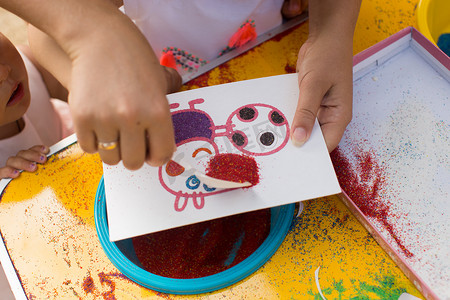 一个孩子用彩沙画画。