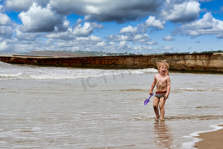 一个小男孩沿着海边的沙滩奔跑