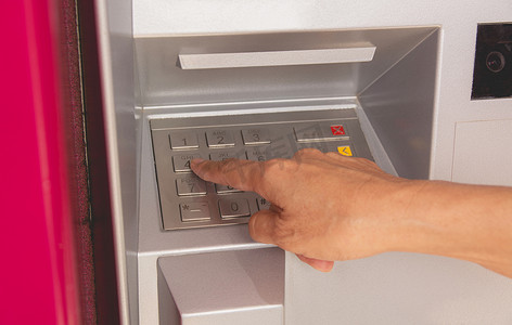 一位女士的手在 ATM 上按下按钮，使用 ATM。