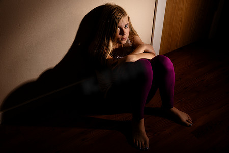 抑郁的孩子摄影照片_独自靠墙坐着的抑郁女孩