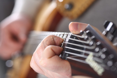 木吉他摄影照片_拿着和弹奏木吉他的男性手