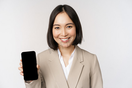 建军节手机海报摄影照片_显示智能手机应用程序界面、手机屏幕、站在白色背景上的亚洲企业女性肖像